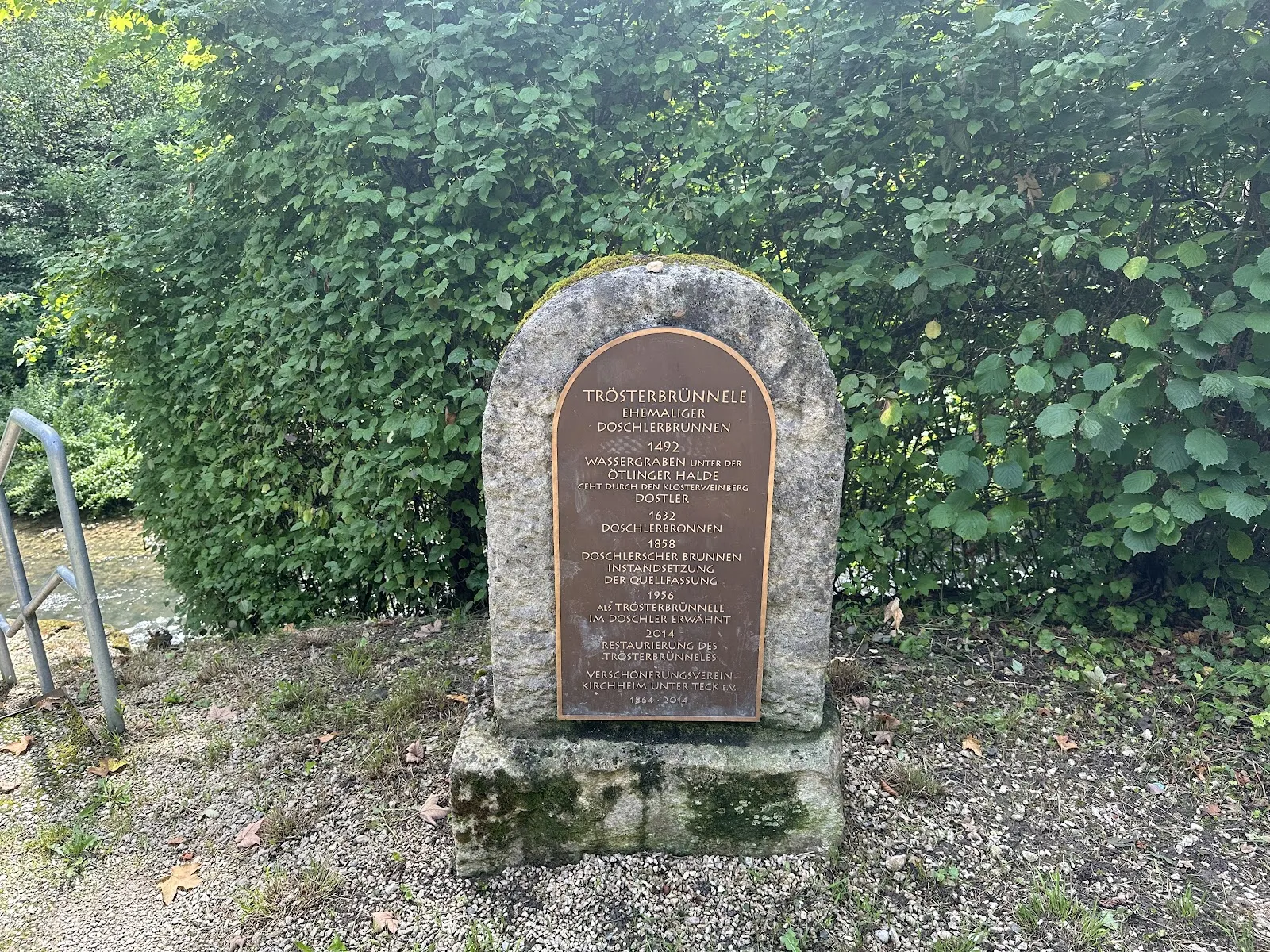 Фонтан Утешителя (Trösterbrunnele) в Кирхгайм-унтер-Тек, Германия, с каменной кладкой и струей воды.