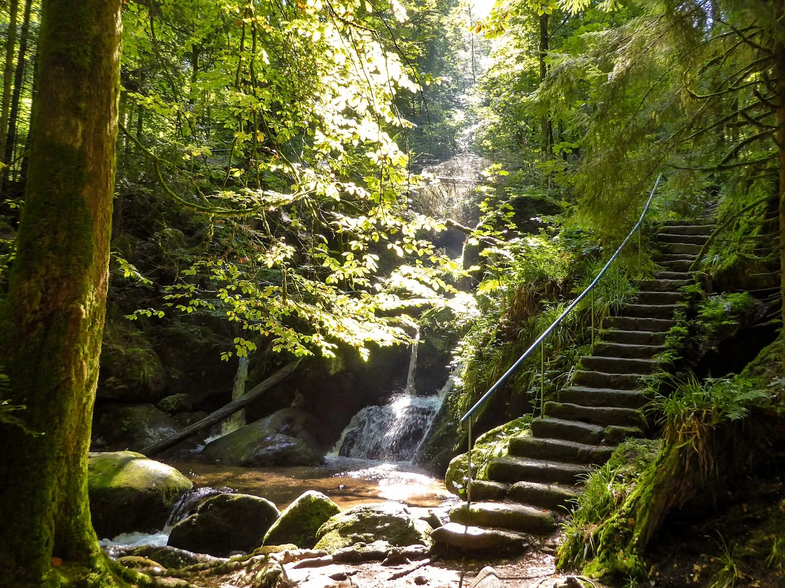 Водопад Гертэльбах, падающий по скалам, окруженный зеленью.