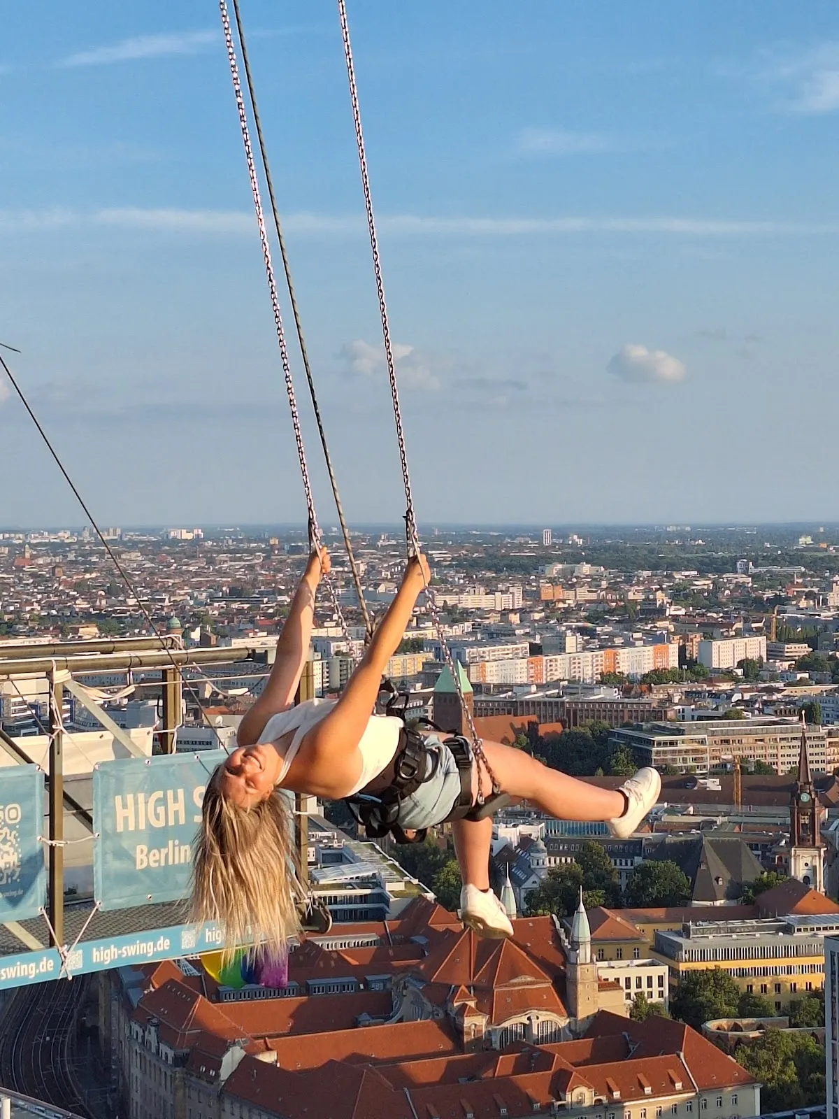 Люди, катающиеся на качелях High Swing Berlin с видом на город