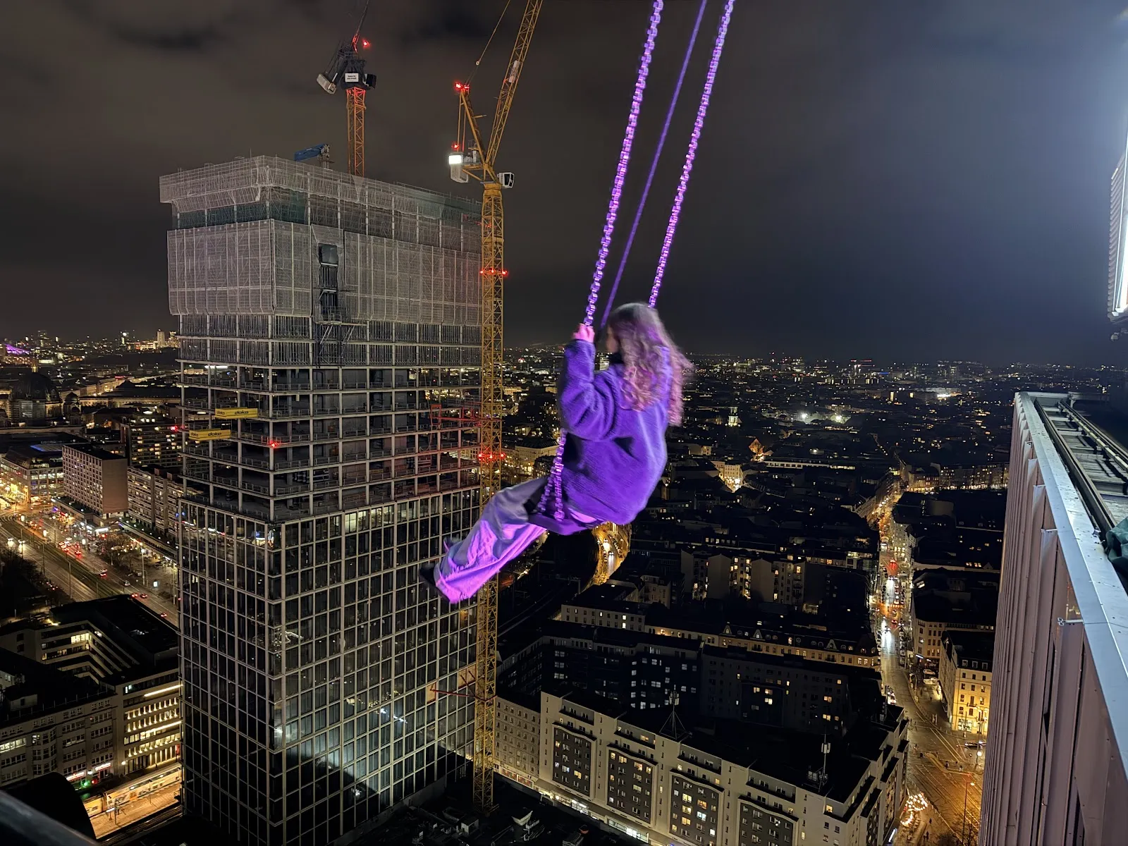 Люди, катающиеся на качелях High Swing Berlin с видом на город