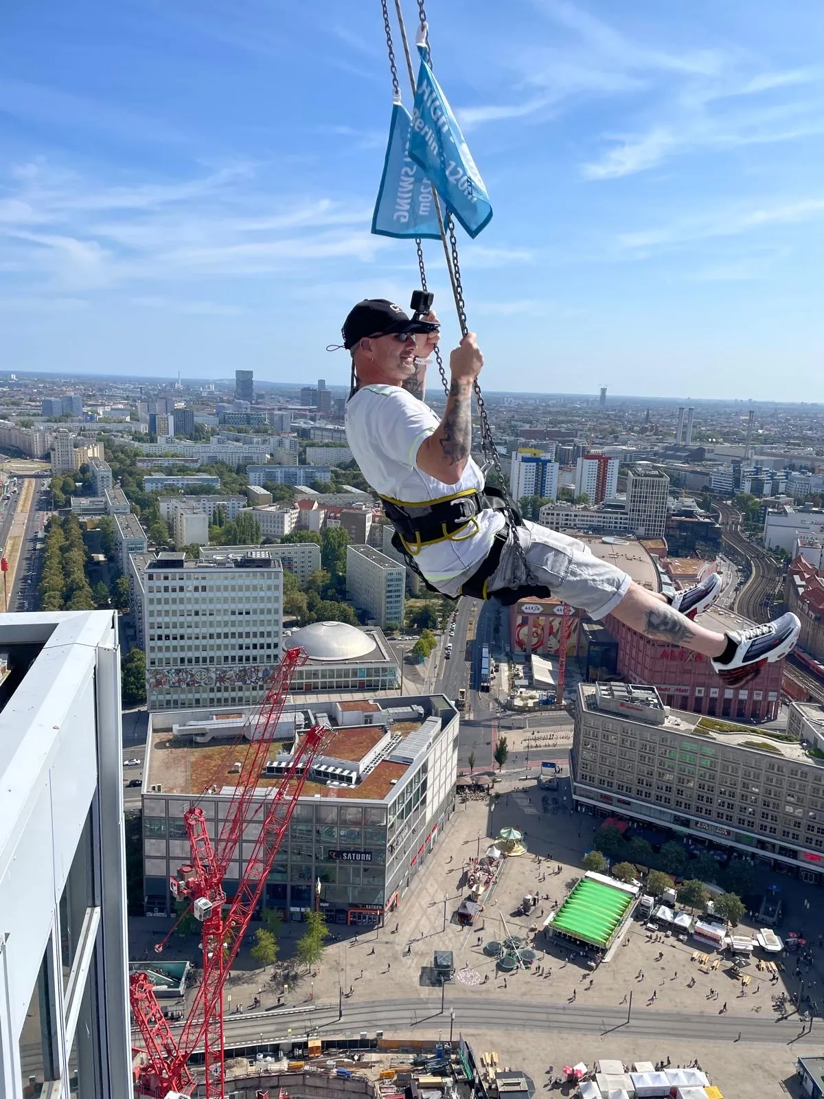 Люди, катающиеся на качелях High Swing Berlin с видом на город