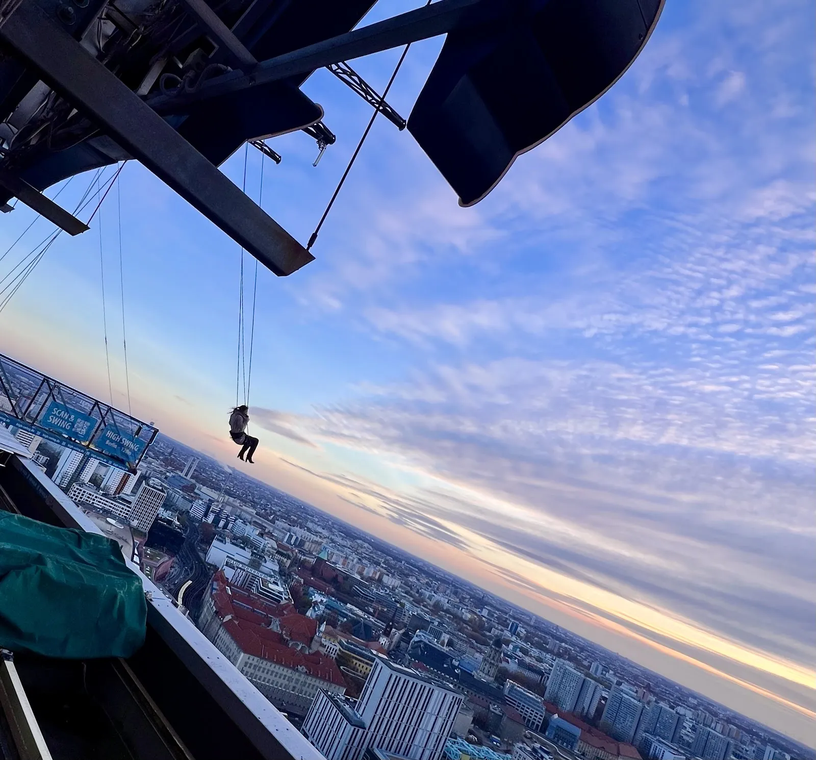 Люди, катающиеся на качелях High Swing Berlin с видом на город