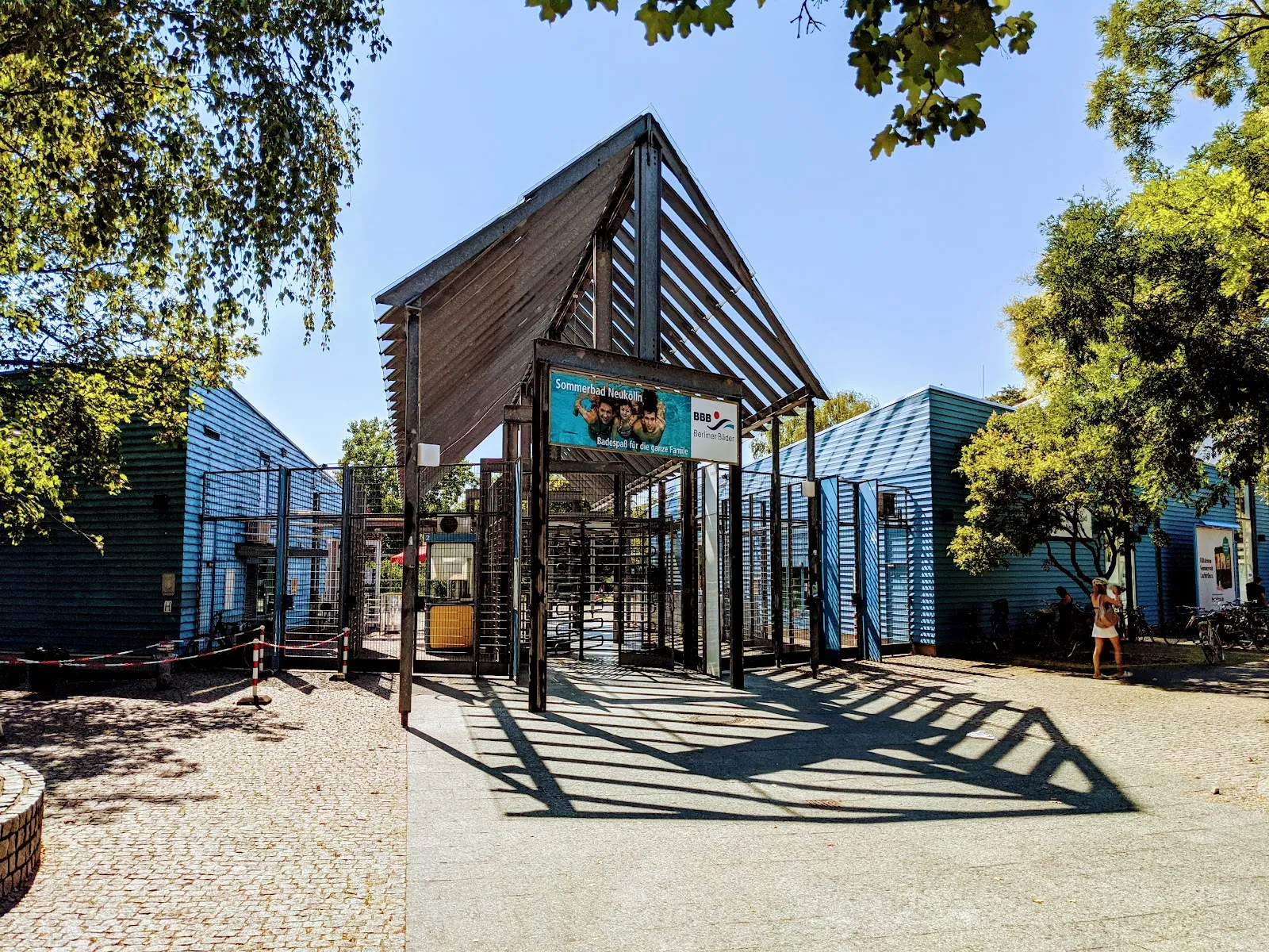 Люди купаются и отдыхают у открытого бассейна Sommerbad Neukölln в Берлине.