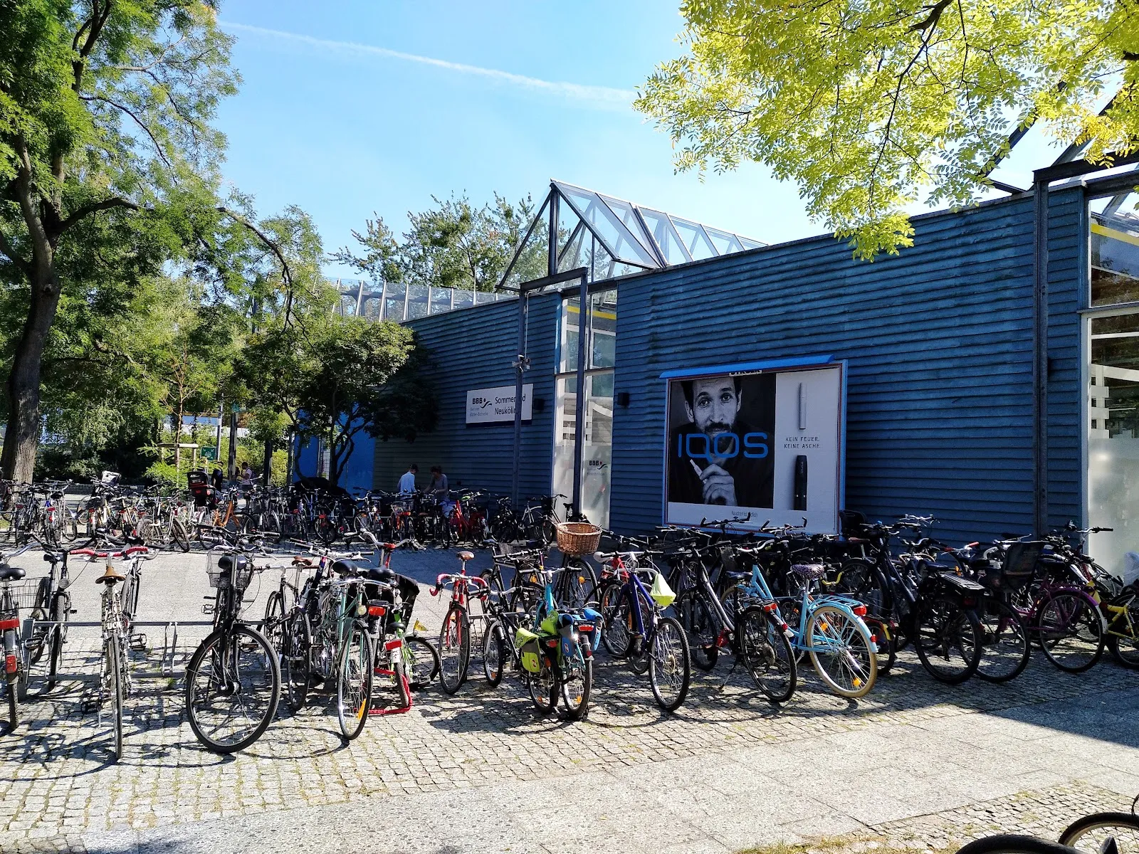 Люди купаются и отдыхают у открытого бассейна Sommerbad Neukölln в Берлине.