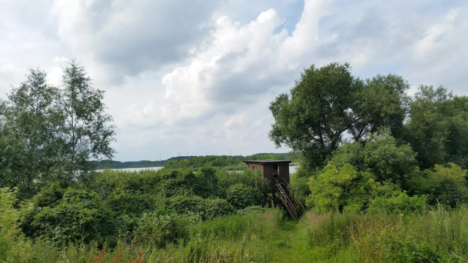 Вид на озеро Мёнхзе с зелёными берегами, символизирующий природу и отдых.