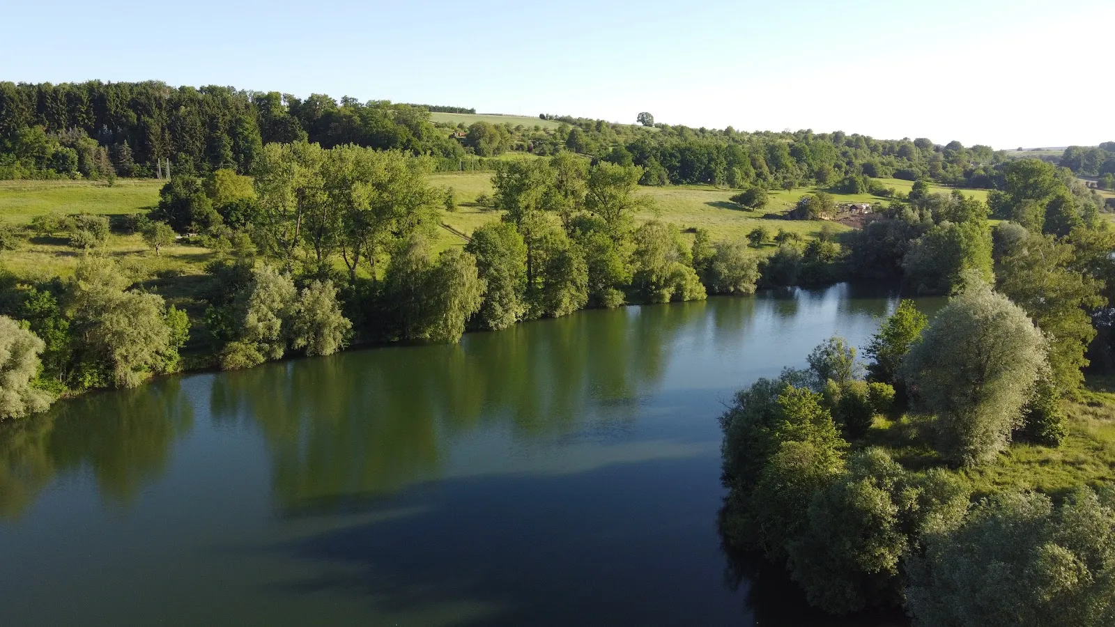 Вид на озеро Бойтванг в Нюртингене, Германия, с зелеными берегами и чистой водой.