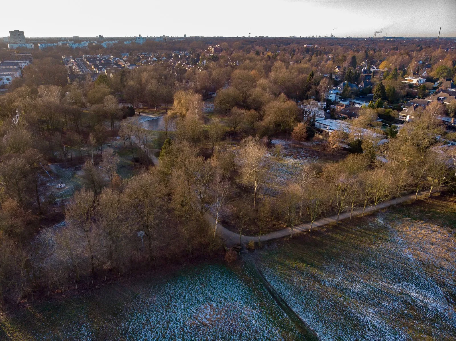 Ухоженный парк с зелеными лужайками и деревьями, где люди отдыхают.