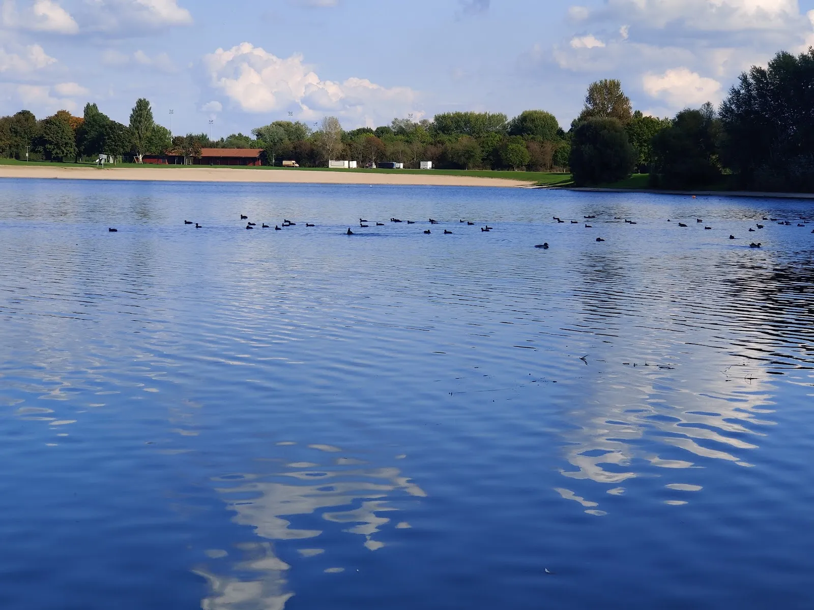 Пляж Аузее, озеро, купающиеся люди, водные виды спорта