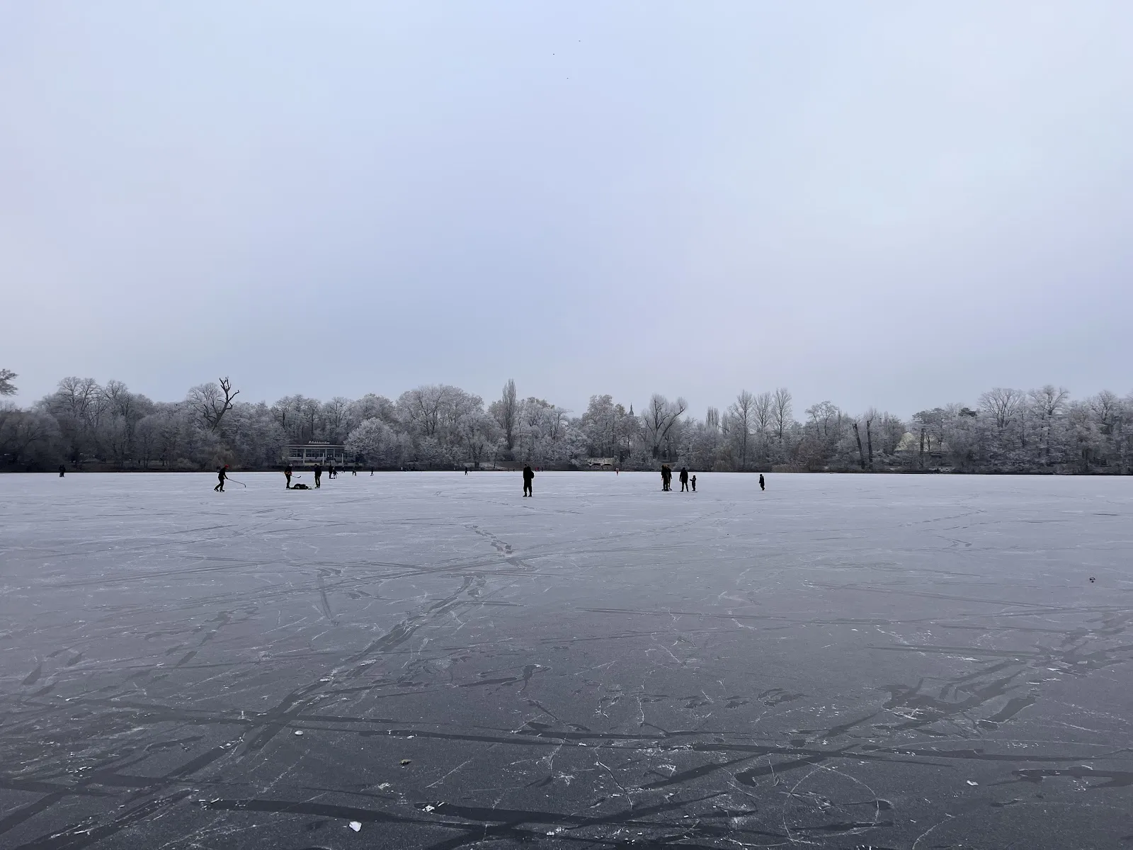 Пляж Вайсензее с людьми, загорающими и купающимися в озере.