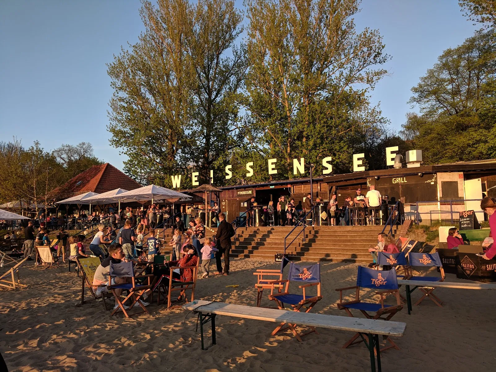 Пляж Вайсензее с людьми, загорающими и купающимися в озере.