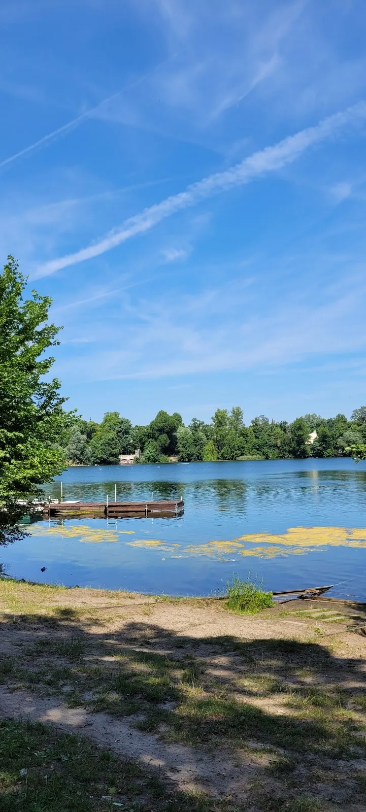 Пляж Вайсензее с людьми, загорающими и купающимися в озере.