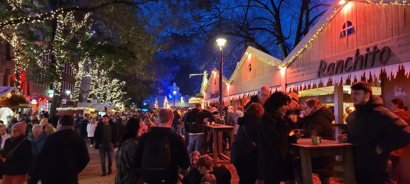 Люди гуляют по набережной Шлахте в Бремене, Германия, с магазинами и кафе.