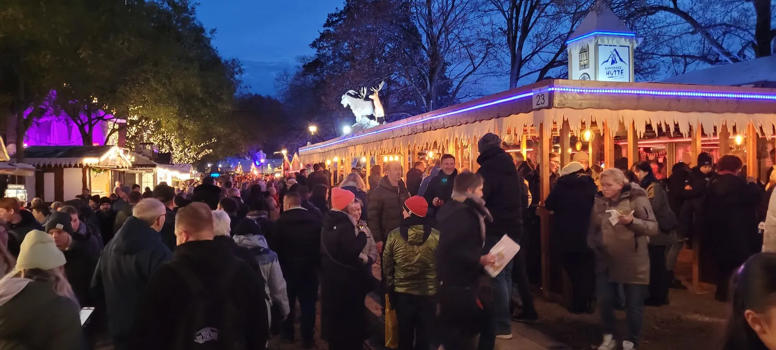 Люди гуляют по набережной Шлахте в Бремене, Германия, с магазинами и кафе.