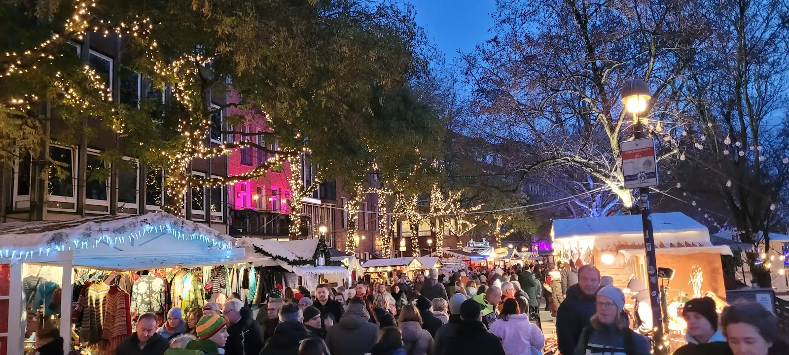 Люди гуляют по набережной Шлахте в Бремене, Германия, с магазинами и кафе.